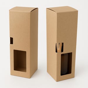 May include: Two brown cardboard boxes, each with a rectangular cutout and a small window. One box contains a brown glass bottle and wooden reeds. The boxes are designed for a fragrance diffuser.