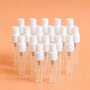 May include: A collection of twenty small, clear glass spray bottles arranged in a grid. Each bottle features a white plastic spray nozzle and a matching white cap. The bottles are empty, cylindrical, and transparent, showing the internal dip tubes.