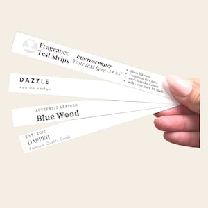 Peut inclure: Bandes de test de parfum blanches avec texte noir. Elles affichent "Fragrance Test Strips", "DAZZLE eau de parfum", et "AUTHENTIC LEATHER Blue Wood". Le texte supplémentaire comprend "CUSTOM PRINT" et des détails sur le produit. Chaque bande mesure environ 12,7 x 14 cm.