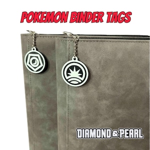 May include: Two gray Pokemon binder tags with silver chains and charms. The charms are round and feature the Pokemon Diamond and Pearl logos. The text "DIAMOND & PEARL" is printed on the right tag.
