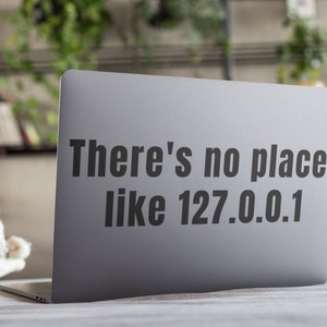 Può includere: Un laptop argentato con un adesivo che dice "There's no place like 127.0.0.1".