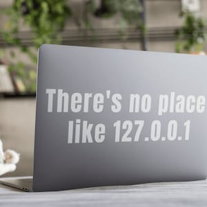 Può includere: Un laptop grigio con un adesivo bianco che dice "There's no place like 127.0.0.1".