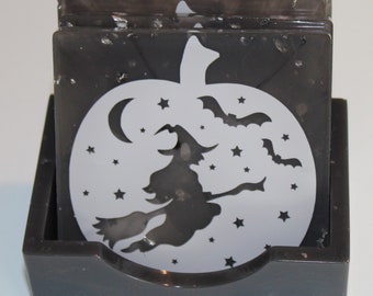 May include: Set of four black and white Halloween-themed coasters featuring a witch flying on a broomstick with bats and stars in a circle. The coasters are in a black holder.