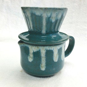 May include: A teal ceramic coffee pot with a white glaze drip design and a matching ceramic pour-over filter.