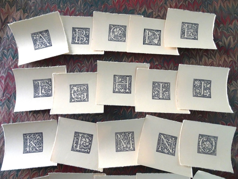 May include: A set of 10 cards with decorative letters of the alphabet, A through J, printed in black ink on a cream background.