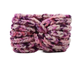 May include: A pink, purple, and white knitted headband with a twisted knot design.