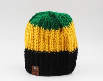 May include: A green, yellow, and black striped knitted beanie with a brown leather tag that says "Island's Pride".