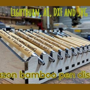 May include: A wooden display stand for bamboo pens. The stand is made of light wood and has a grid pattern. The pens are arranged in rows and are all bamboo with silver accents. The text "Amazon bamboo pen display" is printed on the front of the stand.
