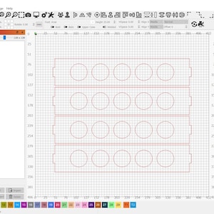 May include: A computer screen displaying a design for a laser cutter. The design is for a rectangular frame with 18 circular cutouts. The design is displayed on a grid with red lines.
