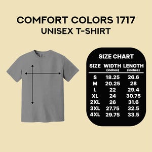 Puede incluir: Una camiseta unisex gris Comfort Colors 1717 con una tabla de tallas. La tabla de tallas muestra el ancho y el largo en pulgadas para las tallas S a 4XL. La camiseta se muestra con flechas que indican las medidas de ancho y largo.