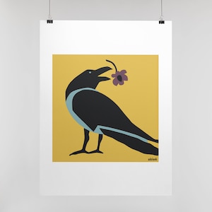 Op de afbeelding: Een vierkante kunstdruk met een zwarte kraai met lichtblauwe accenten op de borst en vleugel, die een paarse bloem in de snavel houdt. De vogel staat tegen een effen mosterdgele achtergrond. De tekst "able6" staat in de rechterbenedenhoek.