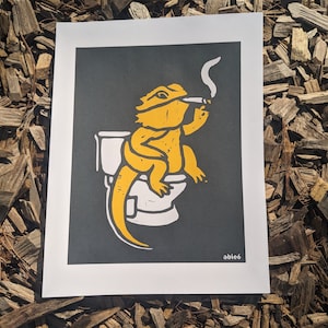 Peut inclure: Un dragon barbu jaune assis sur des toilettes blanches avec une cigarette à la bouche. L'arrière-plan est gris foncé. Le texte "able6" est dans le coin inférieur droit.