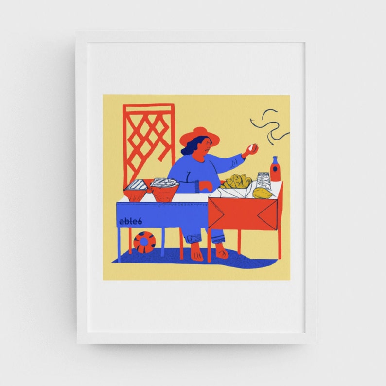 Puede incluir: Una mujer con un sombrero rojo se sienta detr&aacute;s de una mesa roja y azul vendiendo comida. La mesa tiene la palabra "able6" escrita en ella. Hay una celos&iacute;a roja detr&aacute;s de la mujer.