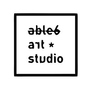 Op de afbeelding: Een vierkante zwarte rand omlijst de tekst able6 art studio in zwarte letters op een witte achtergrond. Het woord able6 is geschreven met een spiegeleffect, gevolgd door het woord art met een klein sterretje en het woord studio eronder.