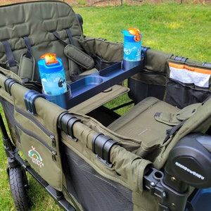 May include: A green wagon with two seats, a black handle, and a black tray with two cup holders. The wagon has a black mesh side and a black and white logo that says "Rainbow Buggy". There are two blue water bottles with orange lids in the cup holders.