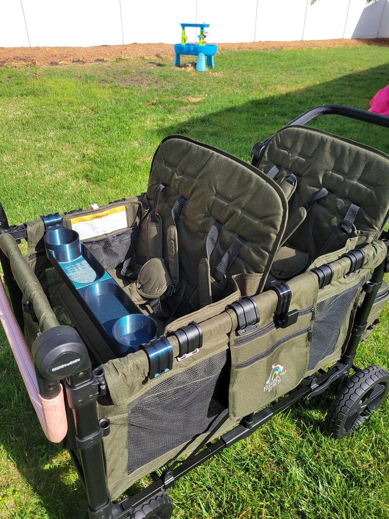 May include: A green wagon with two seats, a cup holder, and a mesh storage compartment. The wagon has a black frame and black wheels. The wagon has a logo that says "Rainbow Ridez" on the side.