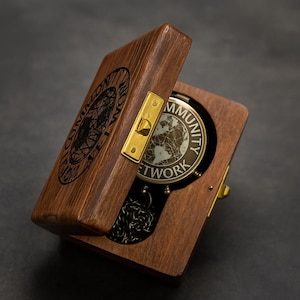 May include: A wooden box with a hinged lid, open to reveal a pocket watch. The watch face features a world map design and the words "COMMUNITY NETWORK". The box is stained a dark brown with brass hardware.