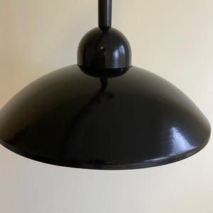 May include: A black pendant light with a round, dome-shaped shade and a coiled cord.