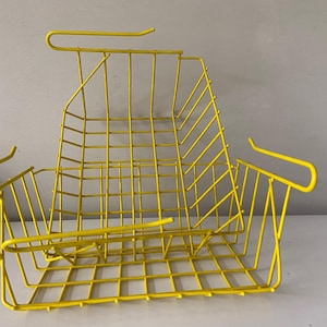 May include: A vibrant yellow wire basket, featuring a rectangular form and a grid-like structure. It has two curved side handles and a top handle. The design is simple and modern, suitable for storage.