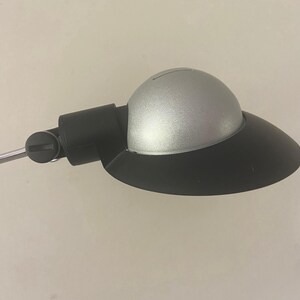 May include: A silver and black desk lamp with a round shade and a flexible arm.