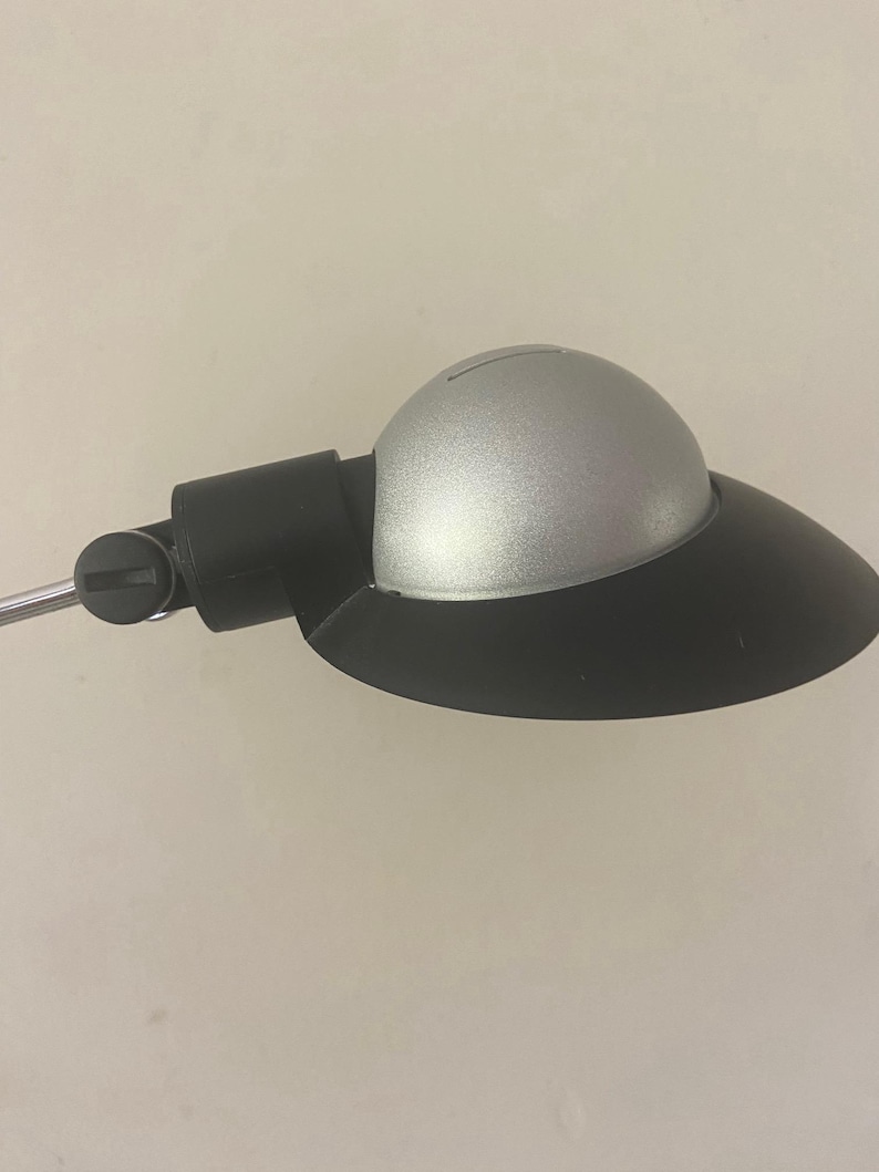 May include: A silver and black desk lamp with a round shade and a flexible arm.