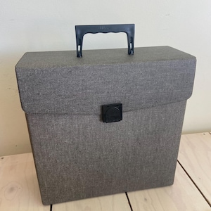 May include: A gray vinyl record storage case with a black handle and clasp. The case is rectangular and has a textured surface. The handle is labeled "Hi-Fi Stereo".