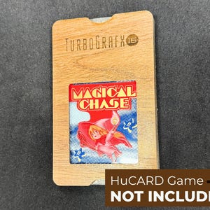 May include: Wooden TurboGrafx-16 HuCARD game holder with a Magical Chase game cartridge. The game cartridge features a red and blue illustration of a character with a wand. The text "HuCARD Game NOT INCLUDED" is at the bottom.