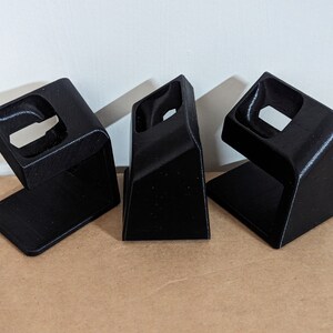 May include: Three black plastic 3D printed stands with a curved design and a circular cutout in the center.