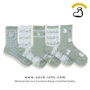 Può includere: Set di cinque paia di calzini verdi e bianchi con un delicato motivo floreale e disegni di coniglietti. I calzini hanno un bordo a festoni e sono realizzati in un materiale morbido e confortevole. www.sock-ists.com