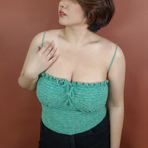 Op de afbeelding: Een groen gecrochete crop top met dunne bandjes. De top heeft een gerimpelde halslijn en een geplooide buste.