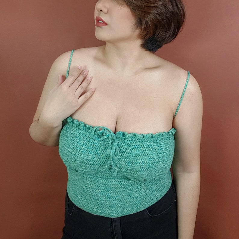 Op de afbeelding: Een groen gecrochete crop top met dunne bandjes. De top heeft een gerimpelde halslijn en een geplooide buste.