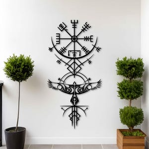 Könnte beinhalten: Ein schwarzes Wandkunstobjekt aus Metall mit einem Vegvisir-Kompasssymbol an der Oberseite, das über einem stilisierten Vogel mit ausgebreiteten Flügeln und nach unten gerichteten geometrischen Pfeilmustern angebracht ist.