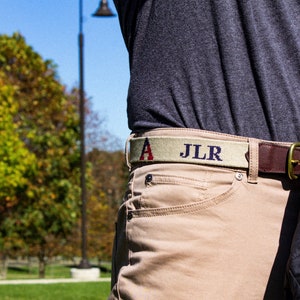 A gentlemen wearing a custom needlepoint belt with his initials added. All of our custom needlepoint belts can have initials added for no extra charge.