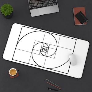 May include: White rectangular mousepad featuring a black and white spiral design. A computer mouse is on the right side of the mousepad. A laptop, coffee cup, and pencils are also visible on a dark surface.