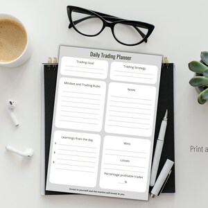 May include: A daily trading planner with sections for goals, strategy, notes, and daily learnings. The planner is on a black spiral notebook, with a pen, glasses, a cup of coffee, and a succulent plant. The text "Print and fill" is visible.