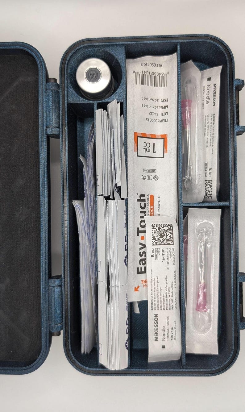 May include: A blue medical case with various medical supplies. The case contains a vial, syringes, needles, and packaging labeled "Easy Touch" and "McKesson Needle". The syringes are 1 cc in size.