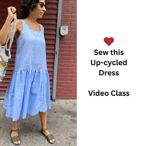 May include: A woman wearing a light blue upcycled dress and sandals, holding a crocheted bag. The text "Sew this Up-cycled Dress Video Class" is displayed on a white background with a red heart.