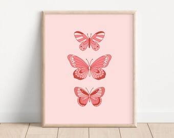 May include: A framed print with three pink butterflies on a light pink background. The butterflies are arranged vertically, with the largest butterfly at the bottom and the smallest butterfly at the top.
