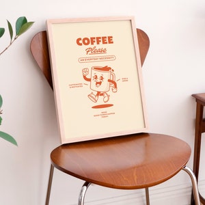 May include: A framed print featuring a cartoon coffee cup character. The text reads "Coffee Please, An Everyday Necessity". The coffee cup is smiling and has arms and legs. The text also says "caffeinated & motivated" and "rise & grind".