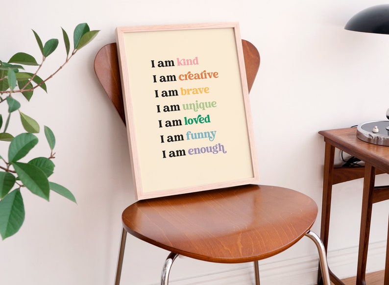 Op de afbeelding: Een ingelijst print met een cr&egrave;mekleurige achtergrond en zwarte tekst die luidt: "Ik ben aardig, ik ben creatief, ik ben dapper, ik ben uniek, ik ben geliefd, ik ben grappig, ik ben genoeg."