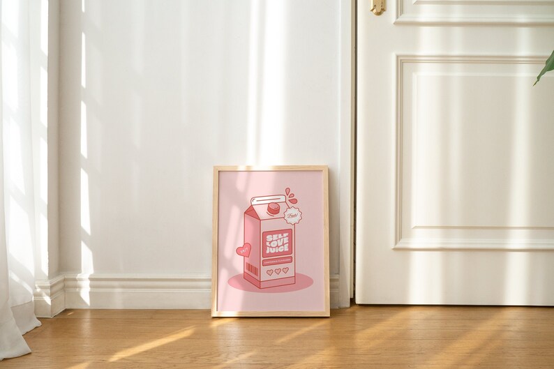 May include: A framed pink and red illustration of a carton of self-love juice. The carton has a red heart and the text "Self Love Juice" on it. The background is a light pink color.