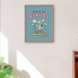 May include: A blue and pink poster with the text "Head in the Clouds" and a cartoon illustration of a smiling earth holding a flower. The earth is wearing yellow shoes and is standing on a green hill.