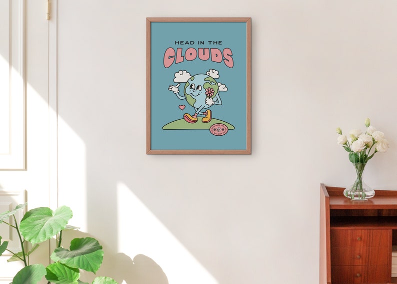May include: A blue and pink poster with the text "Head in the Clouds" and a cartoon illustration of a smiling earth holding a flower. The earth is wearing yellow shoes and is standing on a green hill.