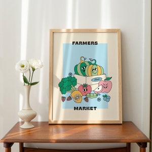 May include: A framed illustration of a farmers market with a blue background. The illustration features a box of fruit with a smiling pumpkin, apple, tomato, and lemon. The text "FARMERS MARKET" is at the top and bottom of the illustration.