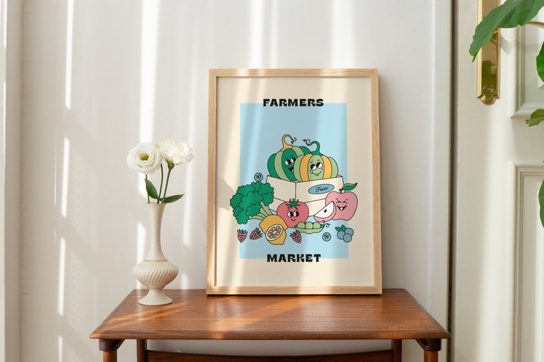May include: A framed illustration of a farmers market with a blue background. The illustration features a box of fruit with a smiling pumpkin, apple, tomato, and lemon. The text "FARMERS MARKET" is at the top and bottom of the illustration.