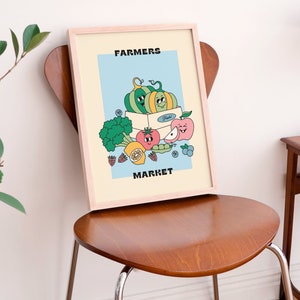 May include: A framed illustration of a box of produce with a smiling green and yellow pumpkin, a red tomato, a green pea pod, a yellow lemon, a pink apple, and blueberries. The text "FARMERS MARKET" is printed in black at the top and bottom of the illustration.