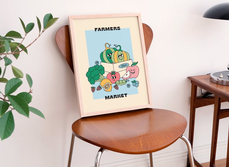 May include: A framed illustration of a box of produce with a smiling green and yellow pumpkin, a red tomato, a green pea pod, a yellow lemon, a pink apple, and blueberries. The text "FARMERS MARKET" is printed in black at the top and bottom of the illustration.