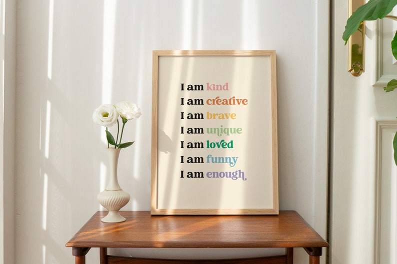Op de afbeelding: Een ingelijst print met een witte achtergrond en de tekst "Ik ben aardig", "Ik ben creatief", "Ik ben dapper", "Ik ben uniek", "Ik ben geliefd", "Ik ben grappig" en "Ik ben genoeg" in verschillende kleuren.