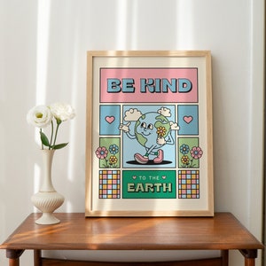 May include: A framed poster with a cartoon illustration of the Earth holding a flower. The poster has a pink, green, and blue color scheme and says "Be Kind to the Earth".