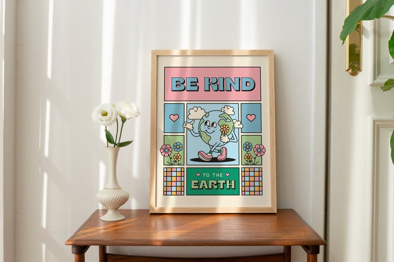 May include: A framed poster with a cartoon illustration of the Earth holding a flower. The poster has a pink, green, and blue color scheme and says "Be Kind to the Earth".